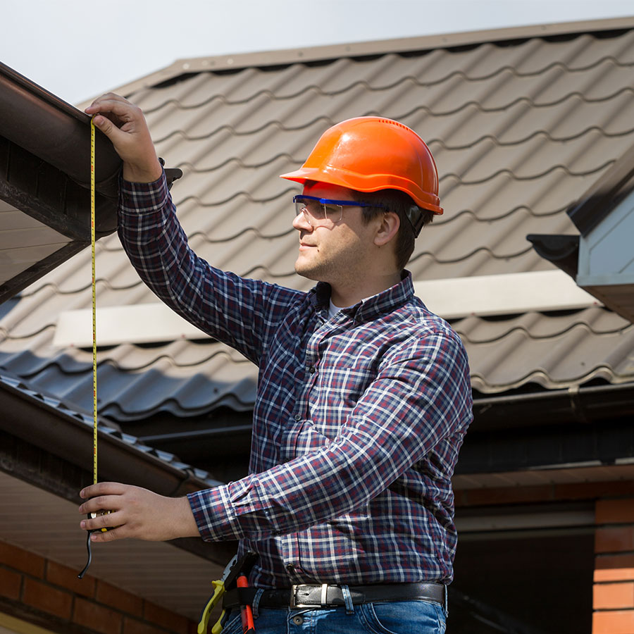 Roofer taking measurements with tape measure.